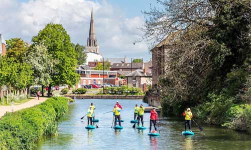 A view of paddleboarders on the river in Chichester with the cathedral in the background